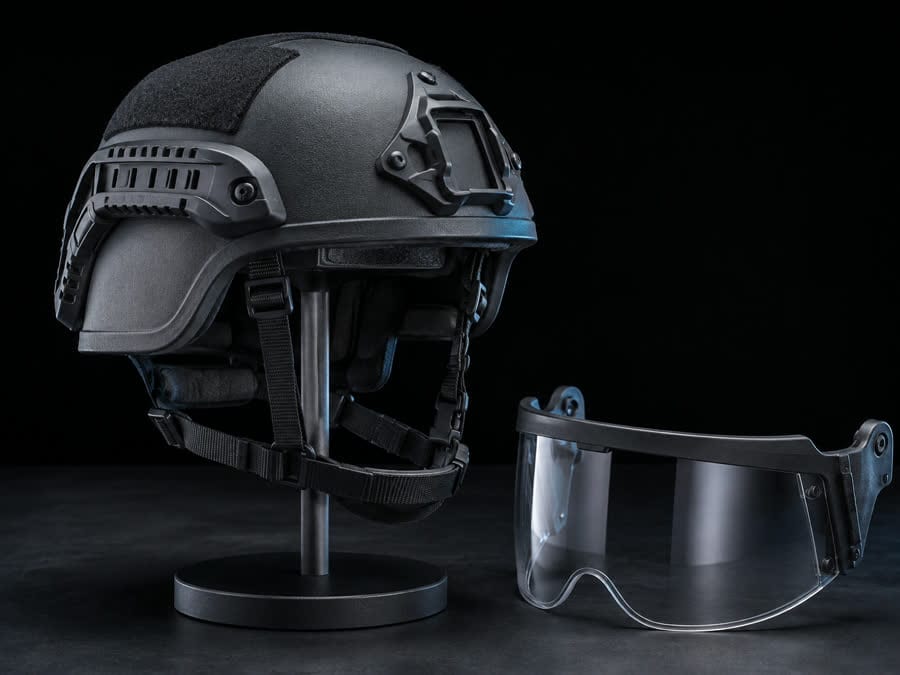 A ballistic helmet on a display stand showing its shell, chin strap and padded liner